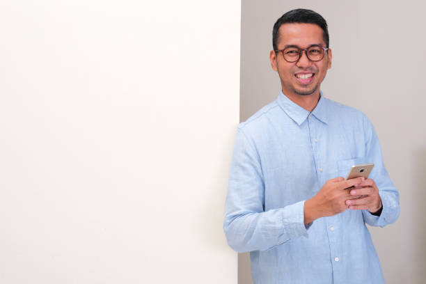 istock A man leaning on the wall showing happy face expression while holding mobile phone 2190505810