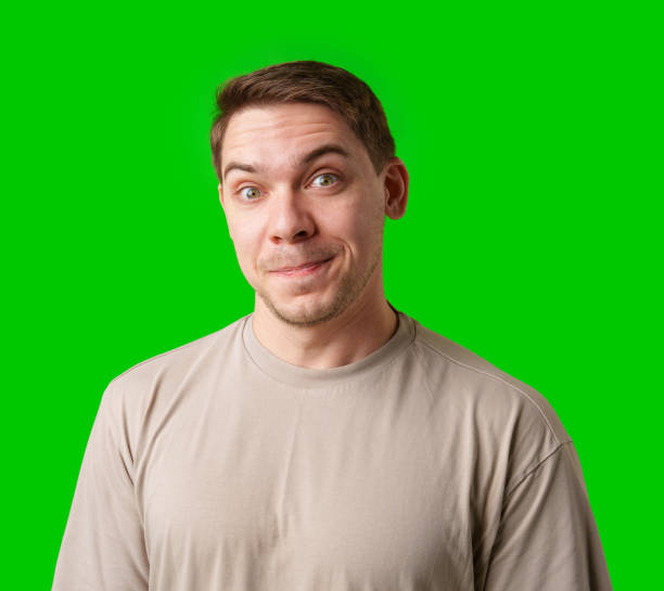 istock Smiling man in a beige shirt poses against a bright green background 2190507177