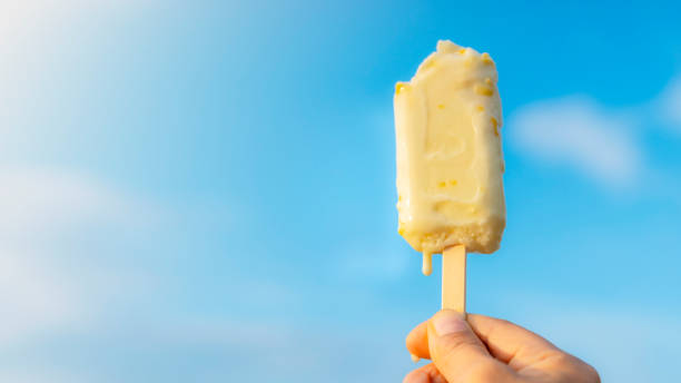 istock Woman's hand holding ice cream raised to the blue sky. In summer 2190507937