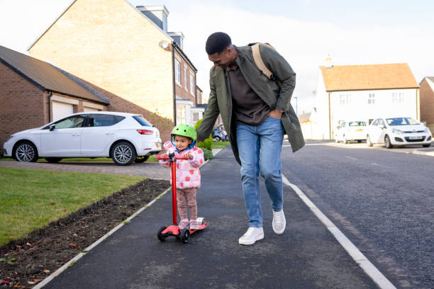 istock Father Helping Daughter Ride Scooter on a Sunny Day 2190508284