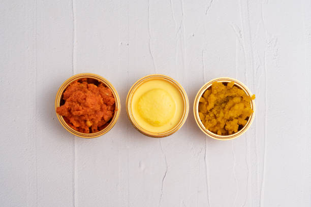 A top-down view of three golden bowls containing popular Indian sweets. The left bowl features Gajar Ka Halwa, a vibrant carrot-based dessert. The centre bowl showcases Rasmalai, a spongy and creamy milk-based treat, while the right bowl holds Moong Dal Halwa, a rich and aromatic lentil-based sweet. Each dessert radiates warmth and indulgence, capturing the essence of Indian festive delicacies