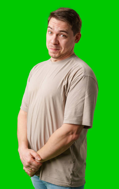 istock A man smiles thoughtfully while standing against a bright green background 2190509609