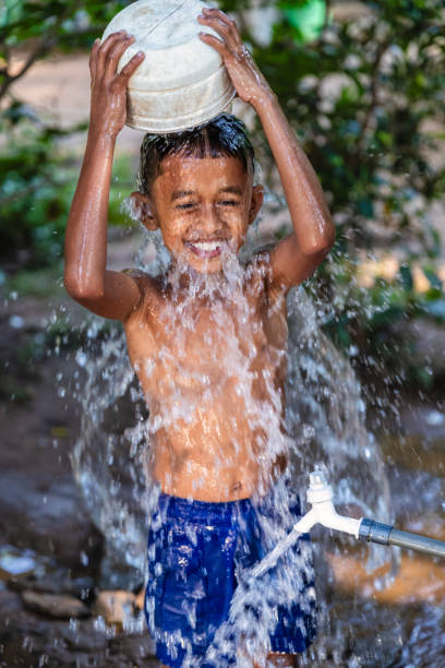 Sri Lankan young boy bathing outside his parents house, Sigiriya, Sri Lanka (Ceylon)