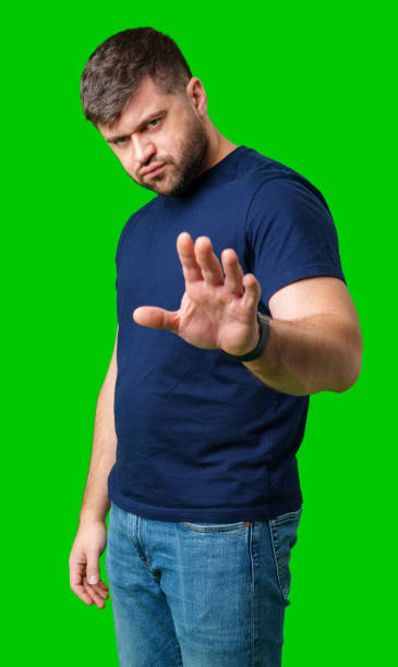 istock A man with a serious expression holds up both hands in a stopping gesture against a bright green background 2190510065