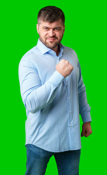 istock A strong man with fists raised, smiling confidently, on a bright green background 2190510124
