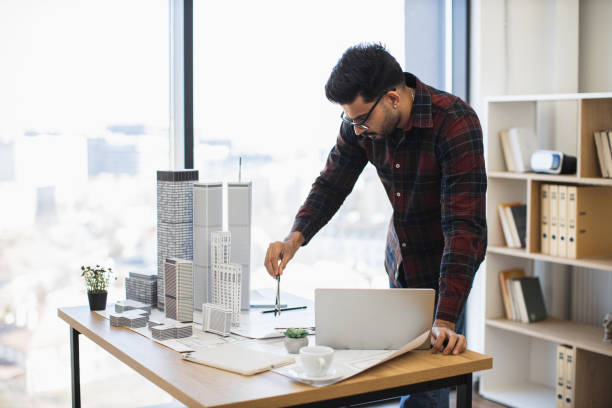 istock Indian architect measuring building model in modern office 2190510249
