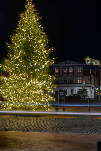 Christmas tree adorned with sparkling lights and light trails stands gracefully, with half-timbered houses on the Paradeplatz in Rendsburg serving as a charming backdrop.