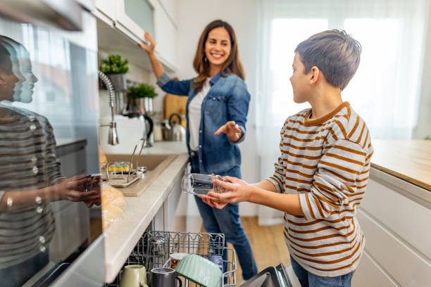 istock Happy mother and son sharing a moment while doing the dishes together in their modern kitchen, promoting family bonding and teamwork 2190513370