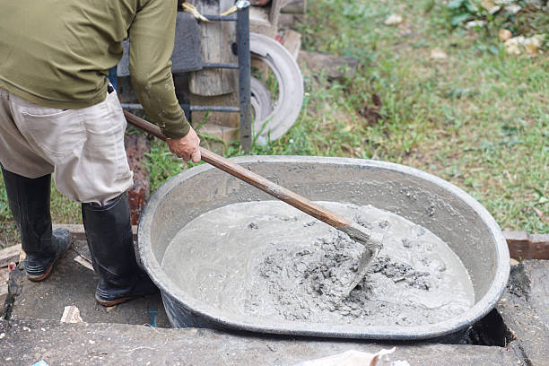 istock Close up worker using a hoe to mix cement powder, sand, stones in basin for mixing cement. Concept. Construction worker job. Hard working. Process of construction work with cement 2190516252
