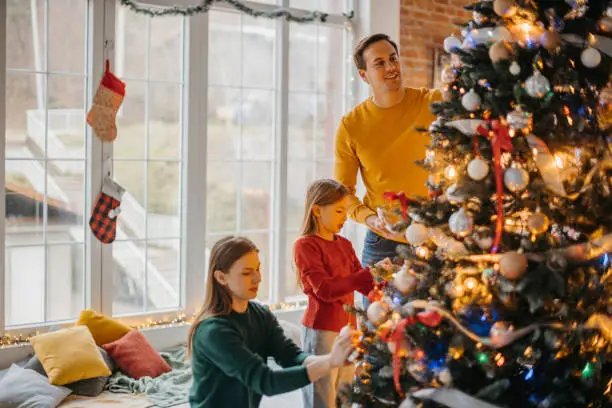 Family decorating a Christmas tree together in a cozy holiday setting Family decorating a Christmas tree together in a cozy holiday setting