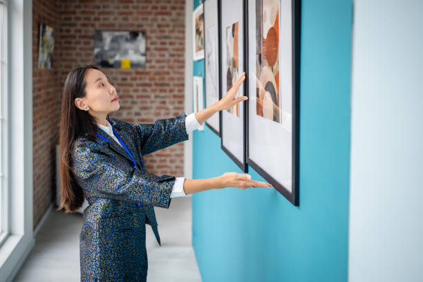 istock Art gallery curator arranging framed art exhibits on a blue wall 2190534644