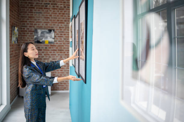 Art curator arranging artwork displays in a modern gallery setting