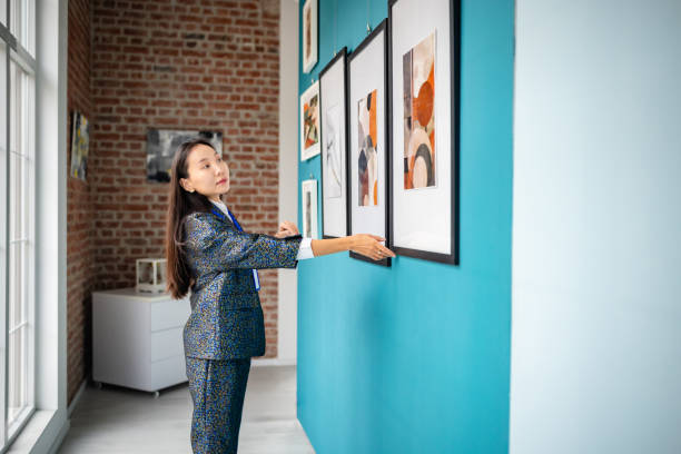 istock Art gallery curator arranging framed pieces on display wall for an exhibition 2190534801
