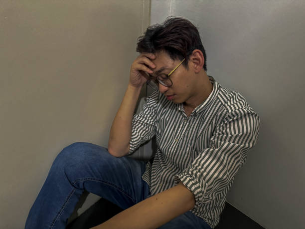 istock A sad man sitting on ground on dark background stock photo 2190537749