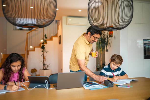 istock Hispanic Father Guides Children in Homework with Joyful Support 2190541035