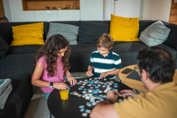 istock Mid Adult Hispanic Father Joyfully Engaging with Kids on Puzzle Activity 2190541080