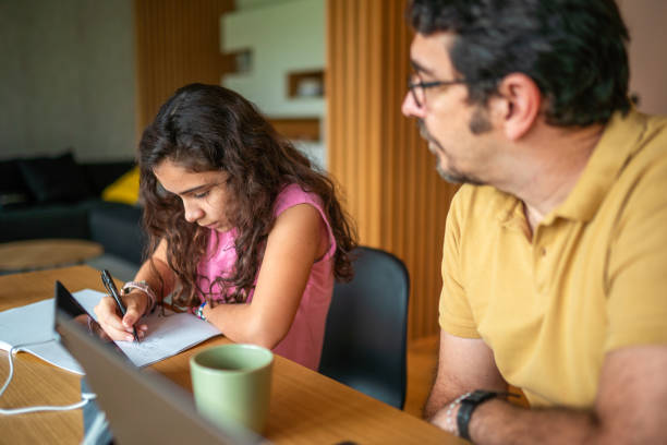 istock Mid Adult Hispanic Father Supports Daughter in Homework Task 2190541090