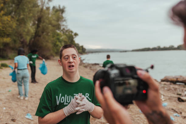 istock Videographer filming volunteer with down syndrome cleaning beach 2190541197