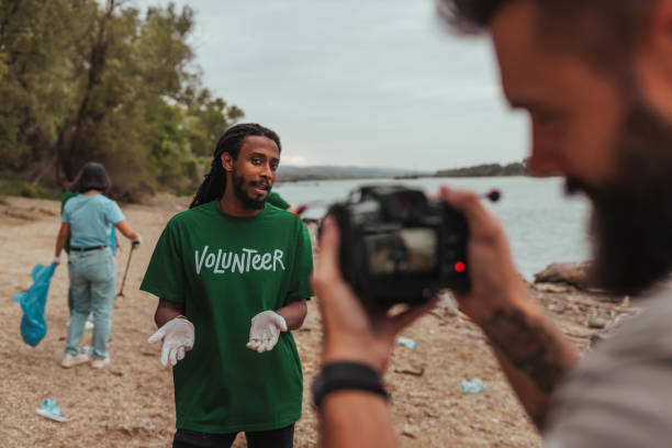 istock Volunteer talking to videographer cleaning beach 2190541209