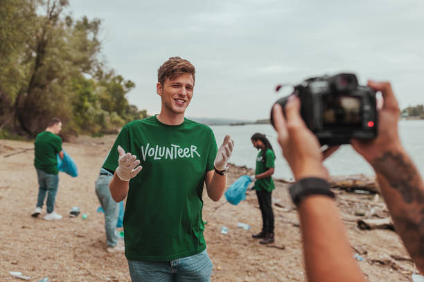 istock Volunteer talking to camera while cleaning beach with team 2190541210