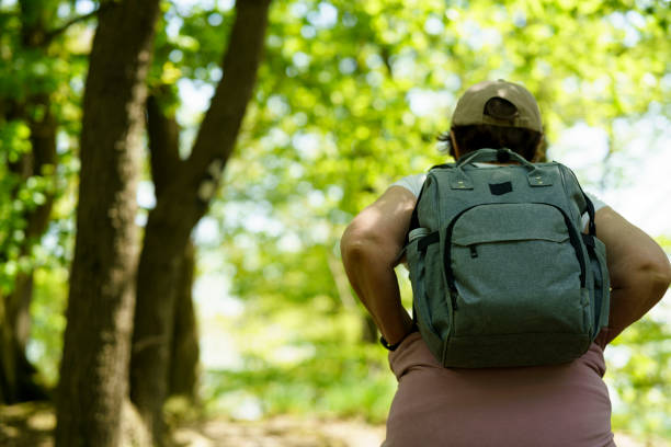 istock Rear view of a woman with a backpack standing in a forest 2190543345