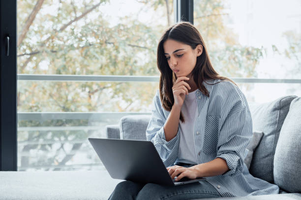 istock Distracted from work worried young woman sitting on couch with laptop, thinking of problems. Pensive unmotivated lady looking at computer, feeling lack of energy, doing remote freelance tasks at home. 2190543389