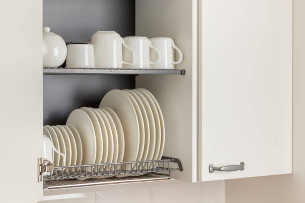 istock A dish-drying rack integrated into a wall cabinet in a modern kitchen with white ceramic kitchenware, plates and mugs, arranged orderly 2190546584