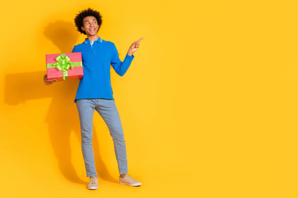 istock Full size photo of nice young man giftbox indicate finger empty space isolated on yellow color background 2190546660