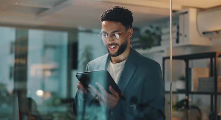 Businessman, trader and night with tablet for investment, research or corporate finance at office. Happy man, employee or investor working late with smile on technology for financial app at workplace