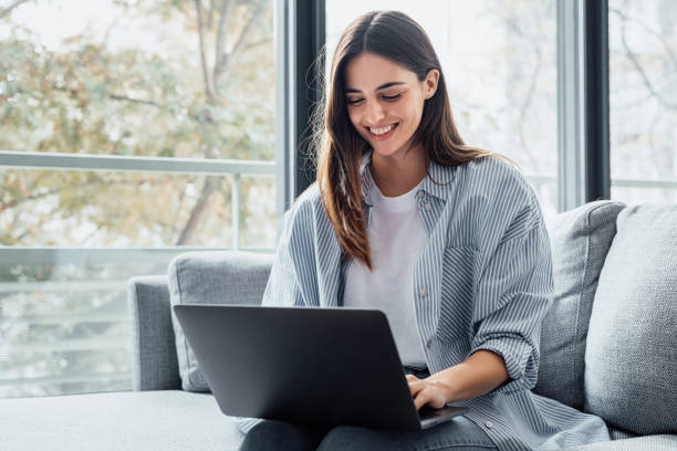 istock Concentrated millennial girl sit on couch working on laptop browsing internet at home during lazy weekend, focused young woman freelancer busy using computer surfing wireless web shopping online 2190548972