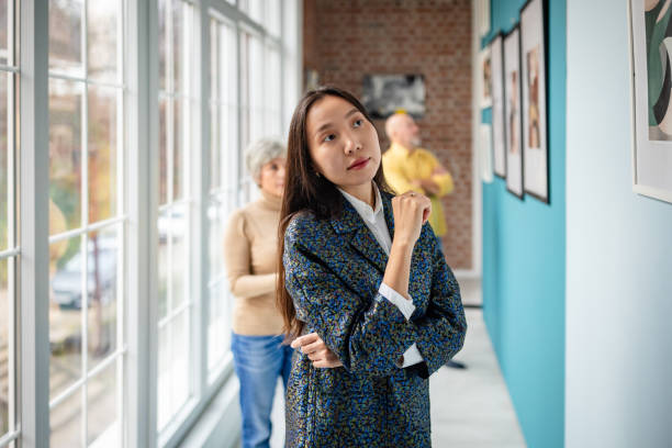 istock Art gallery scene with people observing framed artwork on display 2190550116