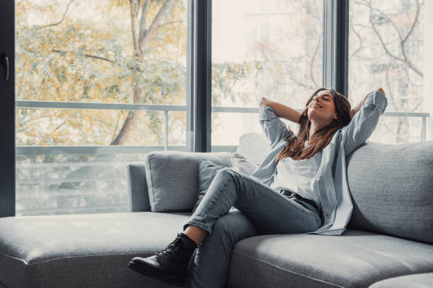 istock Relaxed serene pretty young woman feel fatigue lounge on comfortable sofa hands behind head rest at home, happy calm lady dream enjoy wellbeing breathing fresh air in cozy home modern living room 2190551454