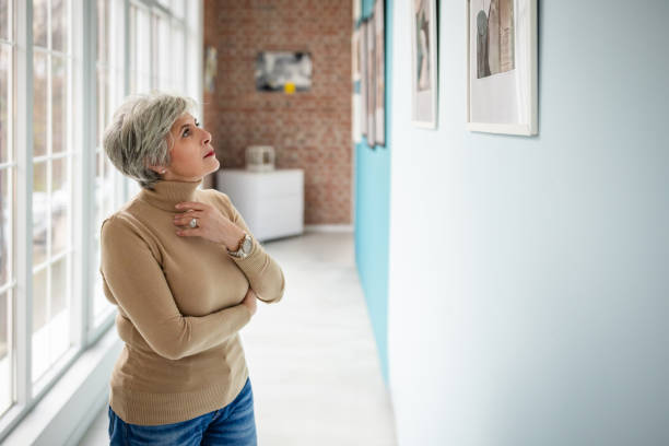 istock Woman in art gallery observing photographs on display with thoughtful expression 2190551578
