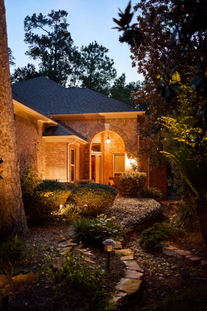 Exterior view of a small stone and brick house surrounded by a garden and trees at night