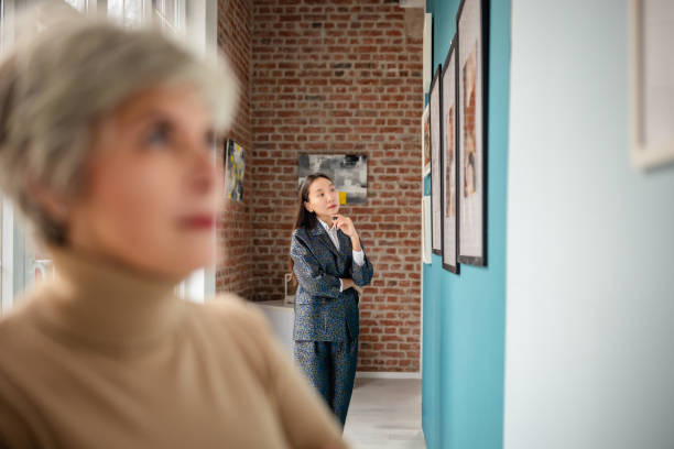 An art gallery features individuals observing artwork while a curator oversees the display, fostering engagement.