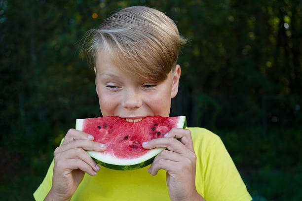 Cheerful boy with a watermelon in a green forest