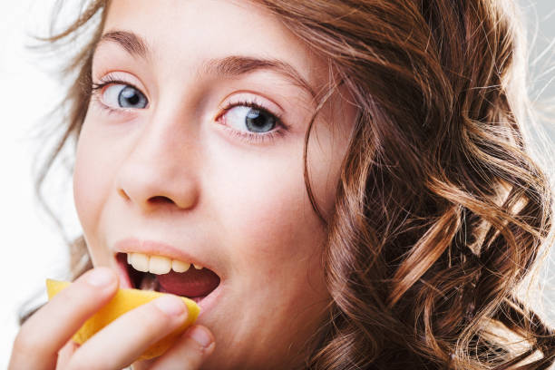 istock Cute girl biting into a slice of lemon with a funny expression 2190553323