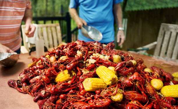Boiled Crawfish with yellow corn and potatoes on table with senior men standing by at retirement home backyard