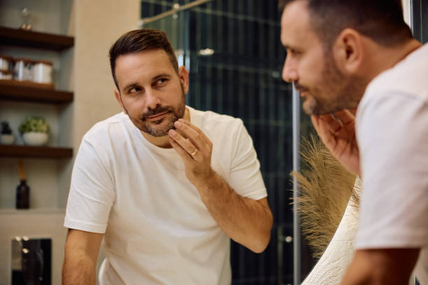 istock Smiling man looking himself in a mirror in the bathroom. 2190557082