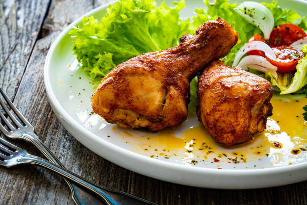 istock Barbecued chicken drumsticks with fresh vegetables on wooden table 2190559574