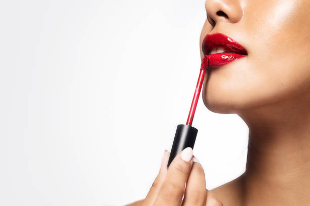 istock Beautiful woman applying red lipstick on isolated white background 2190564233