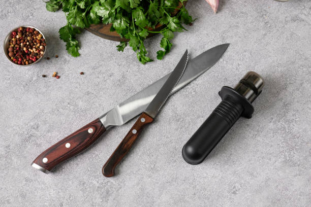 istock Close-up a kitchen knifes and hand sharpener on a table in a home kitchen. There is a cutting board, green coriander, onion, pepper and garlic on the table. 2190566163