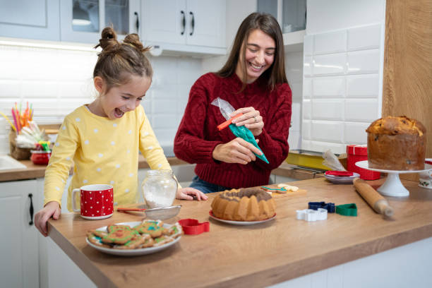 istock Mother and her little daughter create Christmas cookie masterpieces with icing 2190566554
