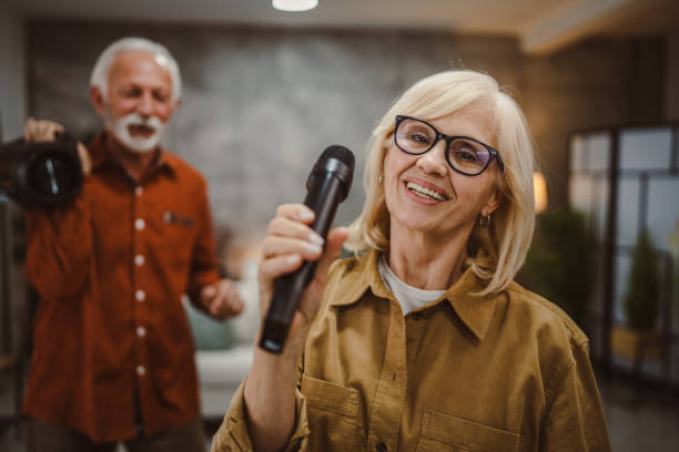 istock senior woman sing karaoke on microphone with senior man behind her 2190567255