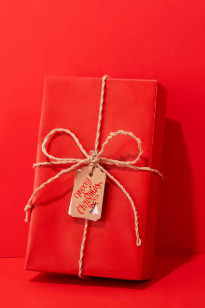 Red gift box on red background with Merry Christmas gift tag