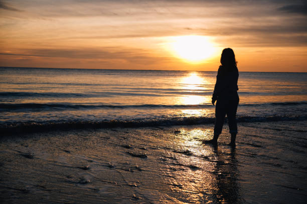istock Woman enjoying stunning sunset at the beach 2190571734