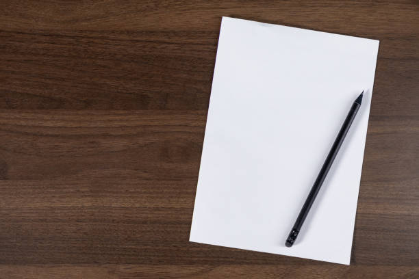 istock black pen resting on blank white paper on wooden desk background for writing ideas or notes. top view 2190577344