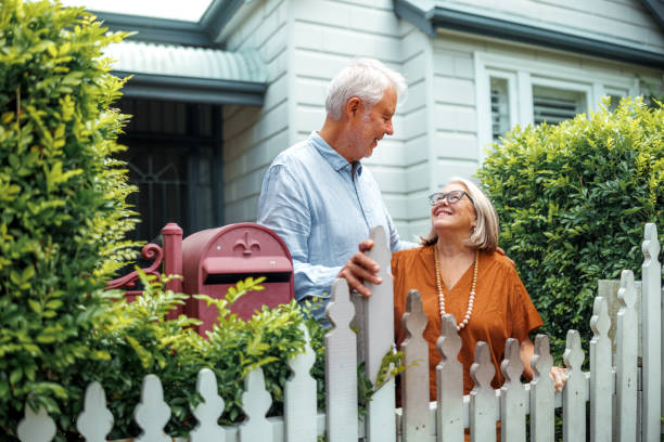 istock Senior couple bonding while standing near fence in their front yard 2190577459