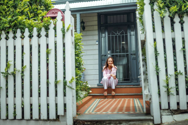 istock Smiling beautiful woman posing for a camera while sitting in front of house 2190577463