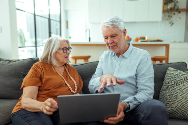 istock Senior couple using laptop while sitting on a sofa at home 2190577530